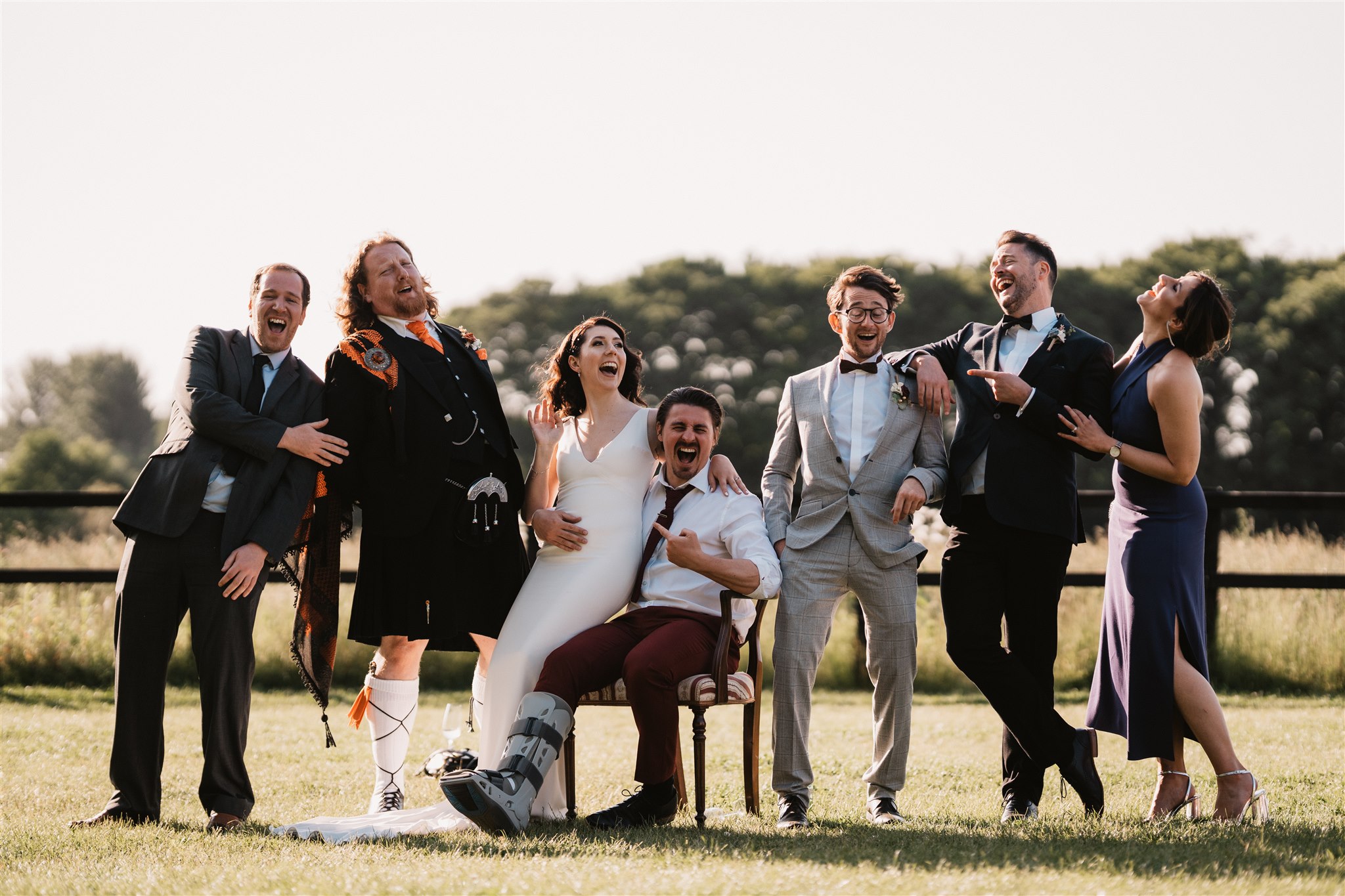 Bride sat on Groom's lap in an outdoor field for a summer British wedding.